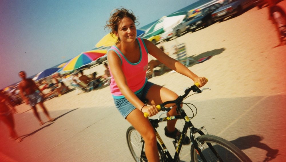 Altes Foto der jungen Frau auf dem Fahrrad an einem vollen Strand